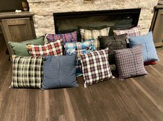 a pile of pillows sitting on top of a wooden floor next to a fire place