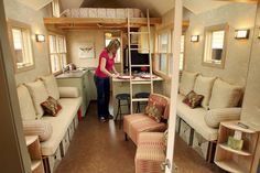 a woman standing in the living room of a mobile home with couches and tables