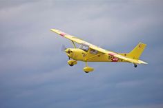 a small yellow plane flying in the sky