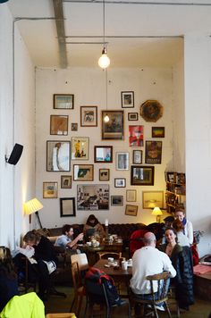 people sitting at tables in a restaurant with pictures on the wall