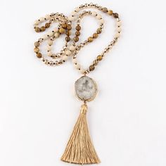 Bring a sophisticated Boho Chic touch to your summer outfit with our Precious Stone Boho Chic Beaded Necklace. A true embodiment of spiritual elegance, harmony and Bohème chic. Immerse yourself in sophistication with this elegant beaded necklace boasting a truly distinctive design. The pendant, created from a raw stone sample, is adorned with a delicate golden rim and a gracefully cascading tassel in a matching hue. Intricately beaded semi-precious stones are woven together to form this stunning Beaded Beige Necklaces, Elegant Festival Beaded Necklaces With Gold Beads, Spiritual Gemstone Beads Necklace For Beach, Spiritual Beaded Long Necklace For Beach, Elegant Gold Beaded Festival Necklaces, Elegant Beaded Crystal Necklaces For Beach, Elegant Beaded Crystal Necklace For Beach, Elegant Adjustable Crystal Necklaces With Gold Beads, Elegant Adjustable Crystal Necklace With Gold Beads