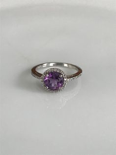 "This lovely halo ring features one round amethyst surrounded by tiny round diamonds that extend to about 1/4\" along the band on either side. The delicate purple shine of the amethyst and the twinkle of the diamonds make this ring simply dreamy! It is marked 14K, is a size 6 1/2 and is in beautiful condition. Please see all photos for details. Thank you for looking! I'm happy to offer layaway on certain items. Please ask for details." Purple Cubic Zirconia Birthstone Ring, Classic Purple Diamond Ring With Halo Setting, Purple Diamond Ring With Halo Setting And Round Cut, Formal Purple Birthstone Ring With Halo Setting, Purple Round Cut Birthstone Ring With Center Stone, Formal Purple Halo Birthstone Ring, Elegant Lavender Amethyst Ring, Classic Amethyst Diamond Ring With Halo Setting, Purple Diamond Birthstone Ring With Round Cut