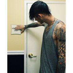 a man with tattoos holding onto a door handle