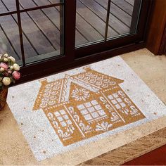 a door mat with a gingerbread house on it next to a potted plant