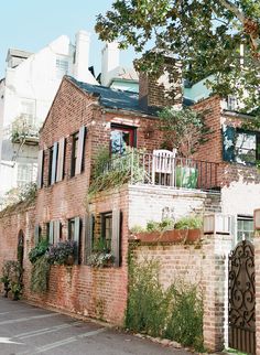 an old brick building with lots of windows and plants growing on the side of it