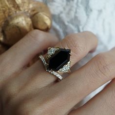 a woman's hand with a gold ring and black stone on it, next to a ginger