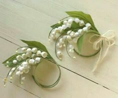 two white flowers with green leaves are sitting on the floor next to each other and tied together