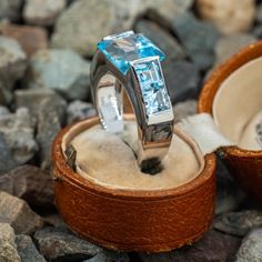 This stunning Italian made topaz ring is centered with one square step cut blue topaz that is channel set and with two square step cut topaz accents at each shoulder. The ring is crafted of 14k white gold. The lower shank has a more oval shape due to its current ring size of 8. This will not be noticed while the ring is being worn. We cannot size this ring down further, however the size can be increased. Modern Blue Topaz Jewelry With Center Stone, Modern Blue Topaz Center Stone Jewelry, Blue Topaz Ring With Tension Setting For Anniversary, Blue Topaz Ring With Tension Setting, Blue Topaz Baguette Cut Ring With Center Stone, Fine Jewelry Blue Topaz Ring With Tension Setting, Anniversary Blue Topaz Ring With Tension Setting, Fine Jewelry Blue Topaz Baguette Cut Ring, White Gold Blue Topaz Ring With Tension Setting