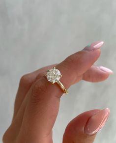 a woman's hand holding an engagement ring with a diamond on the middle finger