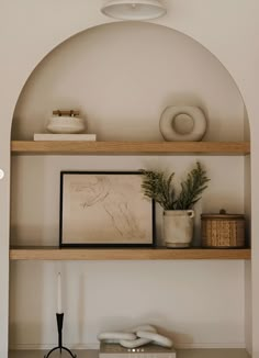 an arch in the wall above a shelf with vases and other items on it