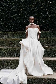 a woman in a white dress is standing on some steps and looking at the camera