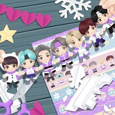 some paper dolls and scissors on a wooden table with snowflakes in the background