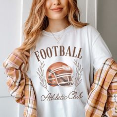 Gear up for game day with our Football Athletic Club Comfort Color Tee. Crafted for comfort and style, this tee is perfect for fans who want to show their support in a laid-back yet spirited way. Emblazoned with the emblem of our Football Athletic Club, this tee exudes team spirit and camaraderie. Whether you're cheering from the stands or watching from home, our tee ensures you'll be representing your team in style. Made from premium materials, this tee offers unparalleled comfort and durabilit Collegiate White T-shirt For Fall, White Collegiate T-shirt For Fall, White Varsity T-shirt For Fall, Sporty Tops For Game Day In Fall, Sports Fan Tops With Team Logo For Game Day, Casual Tops With Team Logo For Game Day, Text Print Tops For Game Day In Fall, Football Season Tops With Team Logo For Sports Fans, Sports Fan Apparel Tops For Football Season