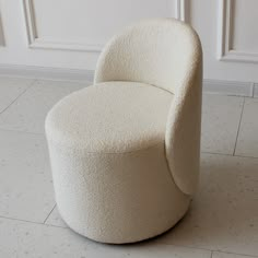 a white chair sitting on top of a tile floor next to a wall and door