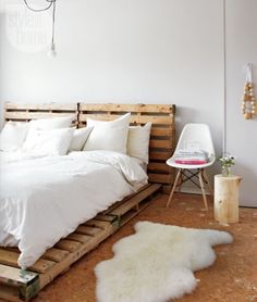 a bed made out of wooden pallets with white sheets and pillows on top of it