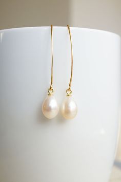 Long Gold Freshwater Pearl Drop Earrings, No. EGH056 :*About This Piece*: ♦︎ These matching, lustrous creamy freshwater pearl teardrops have hints of pink and are truly classy. They are hung on long gold plated sterling silver earrings. Due to the natural formation of these pearls, there will be slight variations in the color and shape of the pearls. ♦︎ Length - 1.7 in (43 mm) ♦︎ Width - .3 in (8 mm) ♦︎ All items from my shop are packaged in padded cardboard jewelry boxes. Custom gifting options Classic Pearl Teardrop Earrings, Classic Long Drop Pearl Earrings With Ear Wire, Classic Pearl White Teardrop (pear Shaped) Earrings, Classic Pearl Teardrop Dangle Earrings, Classic Pearl White Pear-shaped Teardrop Earrings, Graceful Teardrop Pearl Charm Earrings, Classic Pearl Teardrop Earrings For Gift, Hypoallergenic Pearl White Pear Shaped Earrings, Elegant Everyday Cream Jewelry