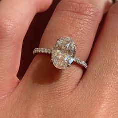 a close up of a person's hand with a diamond ring on their finger