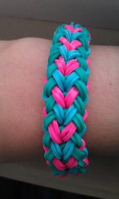 a close up of a person's arm wearing a bracelet with pink and blue braiding on it