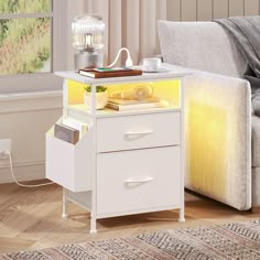 a white table with two drawers and a book on top, next to a couch