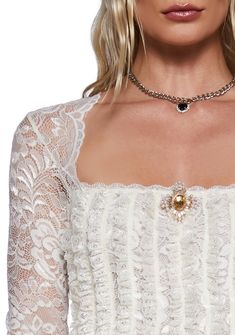 This long sleeve top has a sheer floral lace construction, a front vertical ruffled design, a scalloped lace neckline, and a front removable gemstone brooch with a pin closure. Elegant Long Sleeve Lace Top With Scalloped Edges, Elegant Long Sleeve Scalloped Lace Top, Formal Long Sleeve Tops With Scalloped Lace, Elegant Long Sleeve Lace Top With Ruffles, Long Sleeve Lace Top With Scalloped Lace For Evening, Elegant Ruffled Lace Top, Feminine Long Sleeve Lace Top For Evening, Gemstone Brooch, Lace Neckline