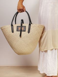 Destined to bring a little sunshine to your look, no matter the season, this tote by Swati brand Khokho Collection has been handwoven by artisans and finished with luxe leather trims for a modern contrast. Try juxtaposing the summery staple with chunky knits and relaxed tailoring for a surprisingly cool effect. - Top handles, tab fastening, open top - Natural fibers, cow leather - Any variations in tone or texture are inherent to the handcrafted nature of each bag - Artisanally crafted by a loca Spring Tote Bag With Leather Trim, Everyday Natural Straw Bag With Leather Trim, Vacation Straw Bag With Leather Trim, Luxury Summer Bag With Leather Trim, Natural Straw Tote Bag With Leather Trim, Natural Straw Bag With Leather Trim, Casual Style, Everyday Straw Tote Bag With Leather Trim, Everyday Leather Trim Straw Tote Bag, Chic Beach Bag With Leather Handles