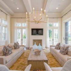 a living room with couches, chairs and a fire place in front of two windows