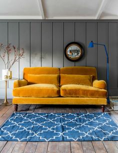 an orange couch sitting on top of a wooden floor next to a blue and white rug