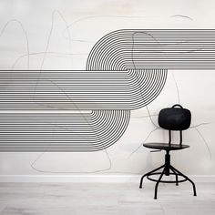 a chair sitting in front of a wall with lines painted on it and an abstract background