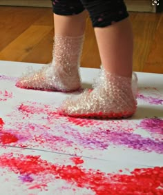 a child's feet in glitter covered shoes on top of a white sheet of paper