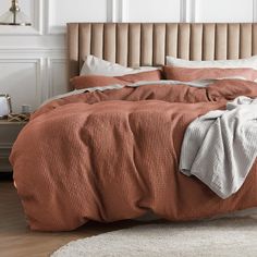 a bed with an orange comforter and pillows