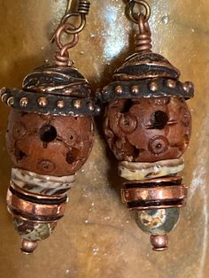 Listen closely and you may hear these earrings beaconing to those who resonate with and earthy, rustic style. The primary focal bead is an intricately carved wooden bead topped with two beautifully made Anna Bronze caps. Below the wood bead is shell "cap", copper spacer bead, and etched agate bead and a tiny copper bead.  The main body of the earring is about 1", with the ear wire the drop length is 1&3/4". The widest point at the dotted bead cap is 1/2".  Feel free to message me if you have any questions and thanks for your interest! Artisan Copper Beaded Earrings As Gift, Artisan Copper Beaded Earrings For Gift, Artisan Copper Beaded Drop Earrings, Artisan Nickel-free Rust-colored Jewelry, Artisan Brown Beaded Earrings For Pierced Ears, Handmade Unique Copper Beaded Earrings, Unique Handmade Copper Beaded Earrings, Artisan Rust-colored Nickel-free Jewelry, Artisan Rust Color Nickel-free Jewelry