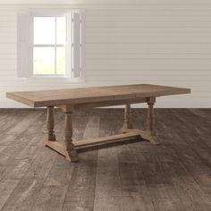 a wooden table sitting on top of a hard wood floor next to a white wall