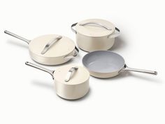 three pots and two pans on a white surface