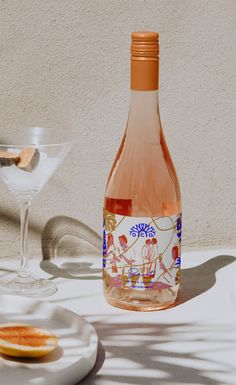 a bottle of wine sitting on top of a table next to a plate with an orange slice