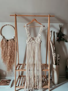 a dress hanging on a clothes rack next to a potted plant and other items