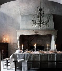 a table with candles on it in front of a fire place and a chandelier