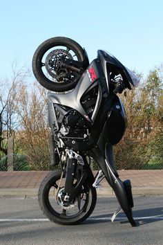 a black motorcycle is parked on the side of the road with it's front tire up