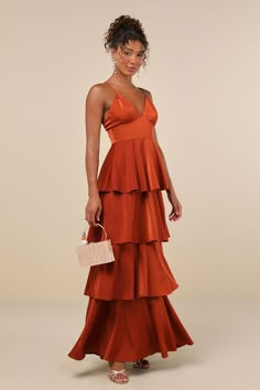 a woman in an orange dress holding a white purse