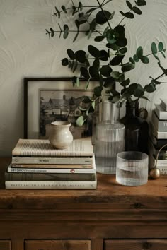 some books and vases are sitting on a dresser