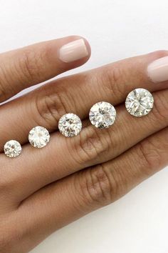 a woman's hand with five different sized diamonds on it, including one large diamond