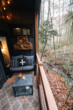 a porch with a couch and coffee table on the front deck in fall foliages