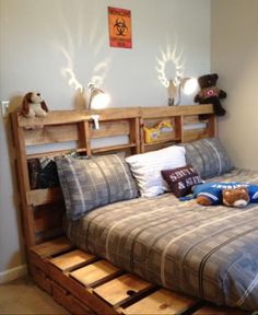 a bed frame made out of pallets with pictures on the wall and below it