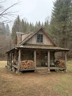 a log cabin in the woods with logs stacked outside