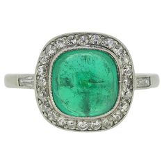 Here we have a lovely emerald and diamond ring that dates back to the Art Deco era. The ring is crafted in platinum and the central emerald is of Colombian origin and possesses a rich green hue. It is surrounded by a border of 'eight' cut diamonds and there is a further baguette cut diamond on each shoulder. Condition: Used (Very Good) Weight: 3.0 grams Ring Size: J (49) Face Dimensions: 11.4mm x 11.4mm Emerald: 7.6mm x 7.5mm x 4.8mm (Approx. 2.0 carats) Diamonds: Approx. 0.20 carats Tested As: Platinum Period: Circa. 1930 Marked: French Platinum Mark (dogs head) Box: The Vintage Jeweller Ring Box Vintage Green Diamond Platinum Ring, Vintage Green Diamond Ring In Platinum, Green Platinum Ring For May Birthstone, Classic Diamond Cabochon Emerald Ring, Vintage Green Diamond Ring With Halo Setting, Green Vintage Diamond Ring With Halo Setting, Classic Green Platinum Ring, Classic Green Platinum Rings, Green Diamond Ring With Halo Setting In Vintage Style