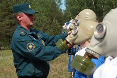 a man wearing a gas mask while holding another man's face in front of him