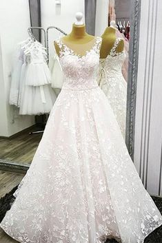 a white wedding dress on display in front of a mirror with other dresses behind it