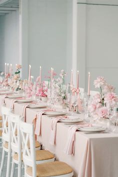 a long table is set with pink flowers and candles for an elegant dinner party or wedding reception