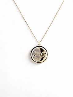 A gold rotating necklace which features the face of the sun on one side and the face of the moon on the other. Comes in 2 sizes. Small charm is 1” wide and hangs from a 16” chain Big charm is 1.5” wide and hangs from a 21” chain Engraved Moon-shaped Brass Necklace, Engraved Brass Moon Necklace, Engraved Moon Shaped Brass Necklace, Moon Phase Coin Necklace With Round Pendant, Gold Moon Charm Necklace With Sun And Moon Design, Celestial Moon Phase Charm Necklace With Round Pendant, Celestial Engraved Round Pendant Charm Necklaces, Gold Moon-shaped Engraved Necklace, Celestial Charm Necklace With Moon Phase Pendant