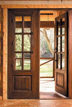 an open wooden door leading to a grassy area with trees in the background on a sunny day