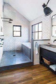 a bathroom with white brick walls and wood floors